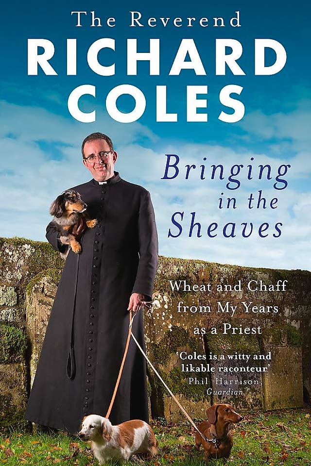 Photo of Richard in a cassock holding a small dog under one arm with two dogs on leads in the other hand