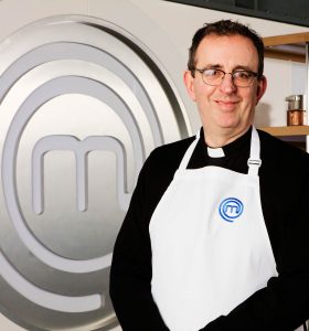 Richard in apron. Masterchef logo in the background