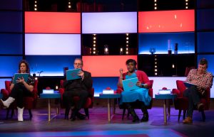 Richard, seated in a row of four celebrities holding iPads on the set of House of Games